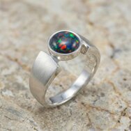 Schwarzer Opal Ring Weißgold massiv mattiert Designer Schmuck modern Farbspiel rot grün Zargenfassung